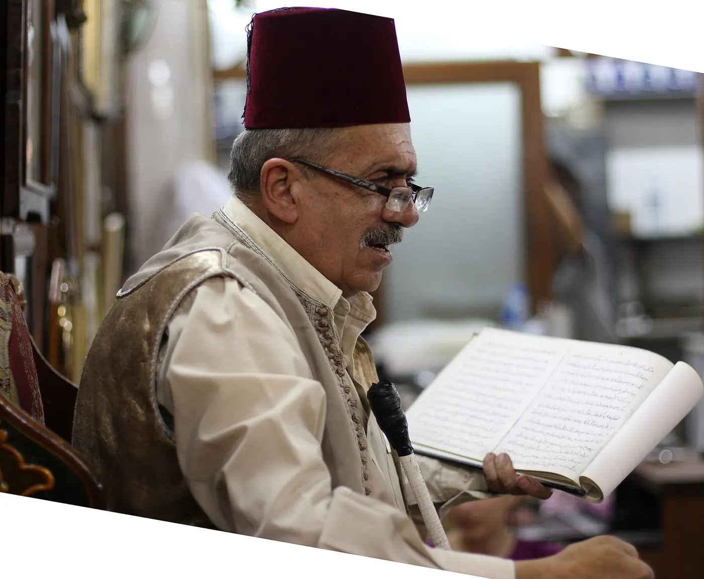 الحكواتي في مقهى النوفرة، يقرأ من كتابه على الكرسيّ المرتفع.